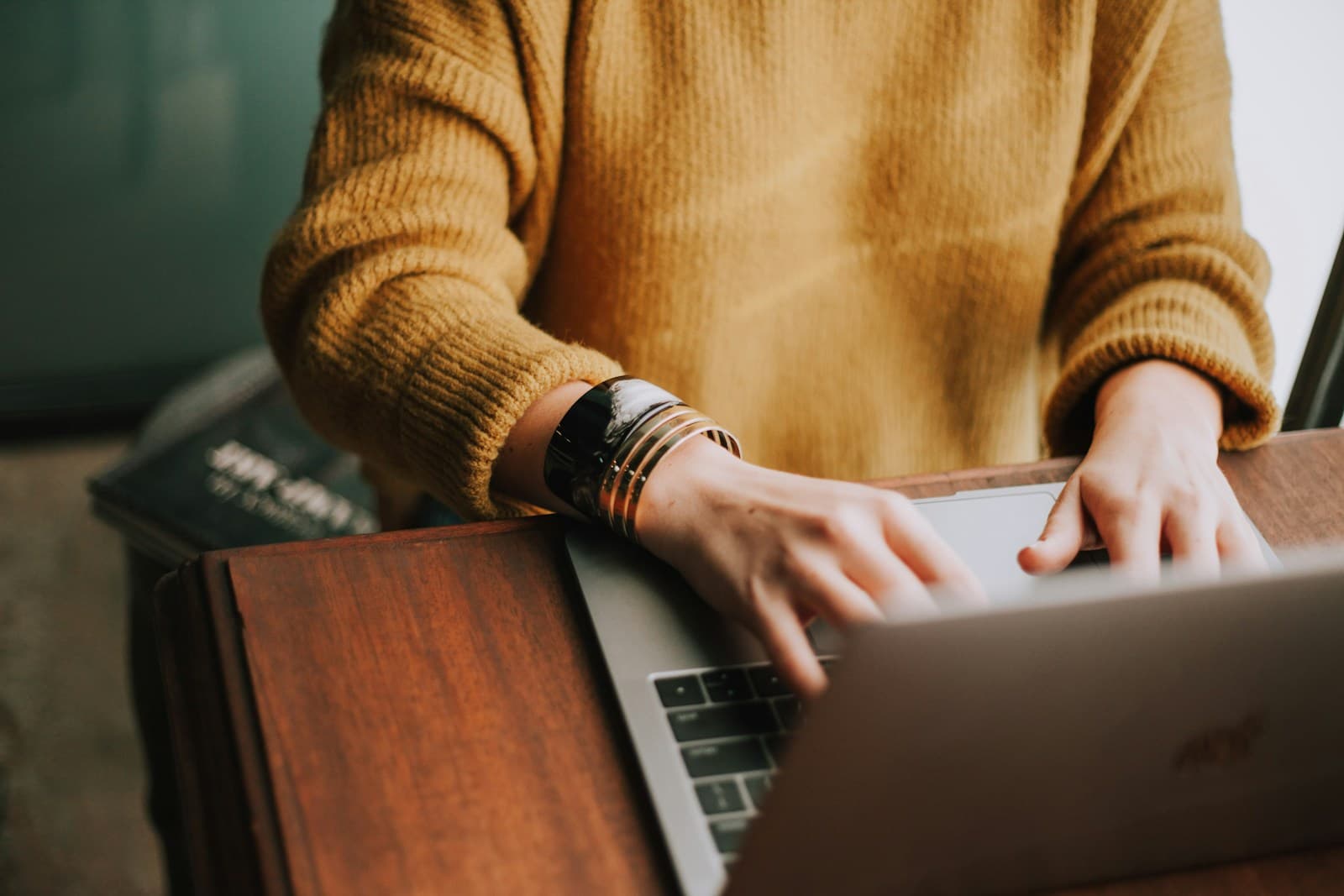 A course creator typing on a laptop at a warm desk
